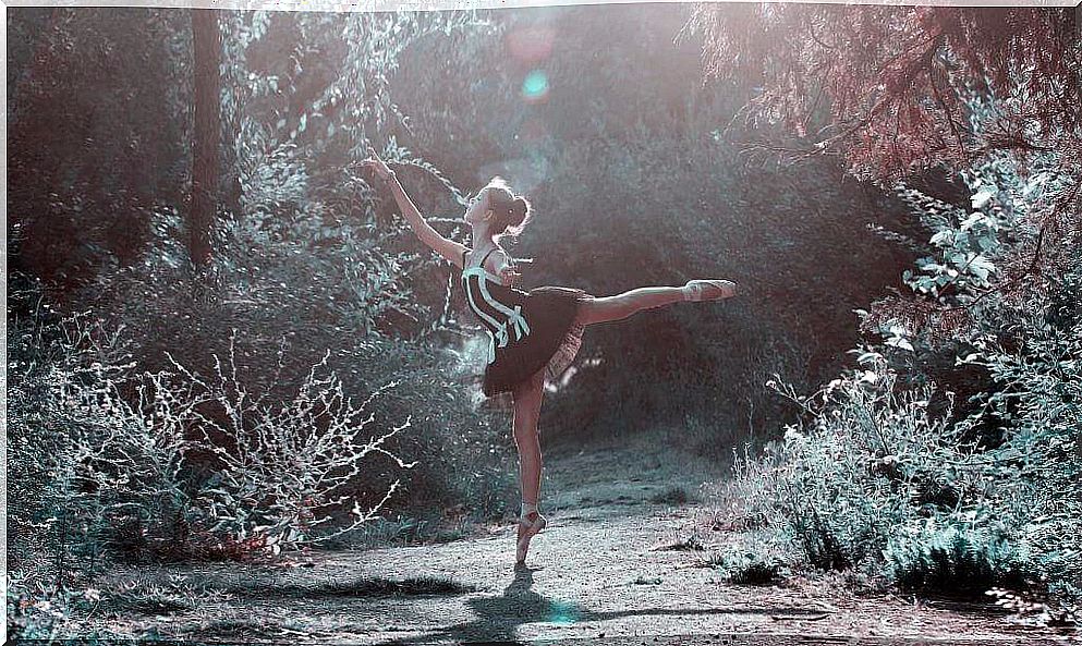 Girl in pointe shoes dances in a black and white ballet dress in a forest clearing.