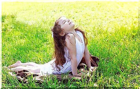 A child is in the meadow taking the cobra yoga pose.