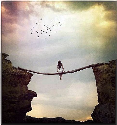 Woman sits on a log over a ravine