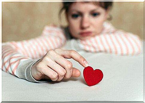 Thoughtful woman touches red heart