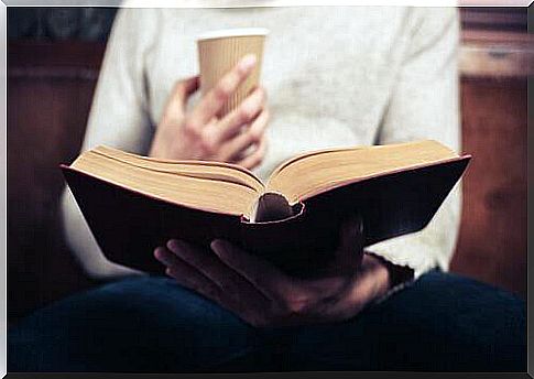 Man with coffee mug reads a book