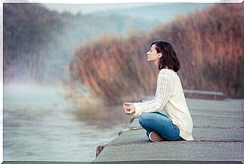 Woman relaxing by a lake using the mindfulness sandwich method