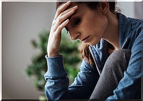 A woman sits exhausted at a table and supports her head with one hand.