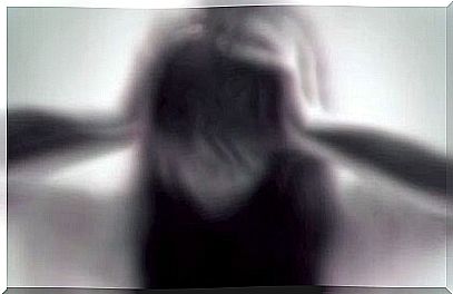 Blurred image of a woman holding her hands to her head