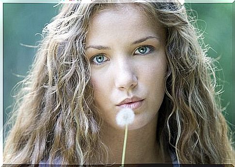 A woman is holding a dandelion