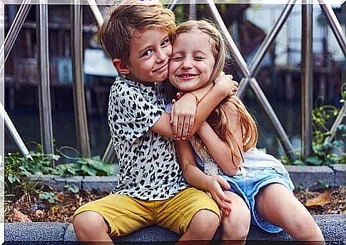 A brother hugs his sister. 