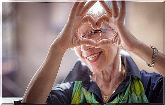 Healthy aging makes you happy - elderly lady forms a heart with her hands