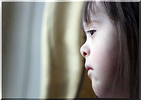 A girl with Down syndrome looks out the window.