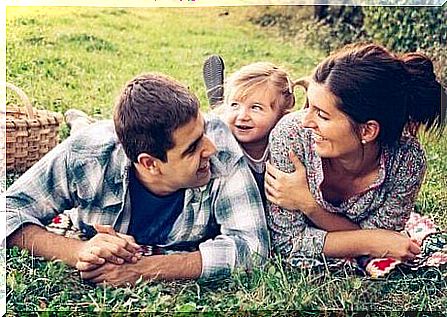 A happy family is lying in a park on a meadow. 