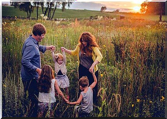 A family is playing a game in a pasture as the sun goes down. 