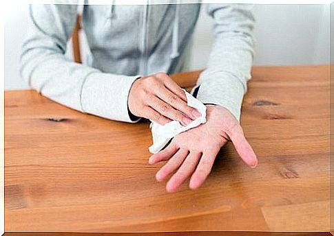 A person wiping their sweaty hand with a napkin.