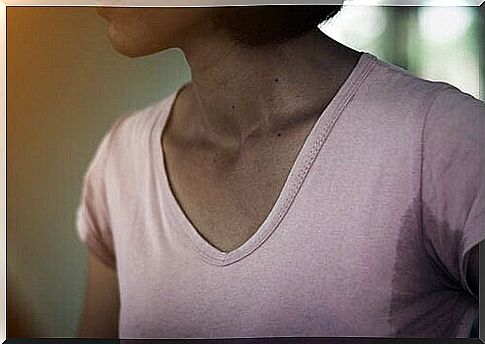 An image showing a woman in a shirt with large armpit sweat stains.