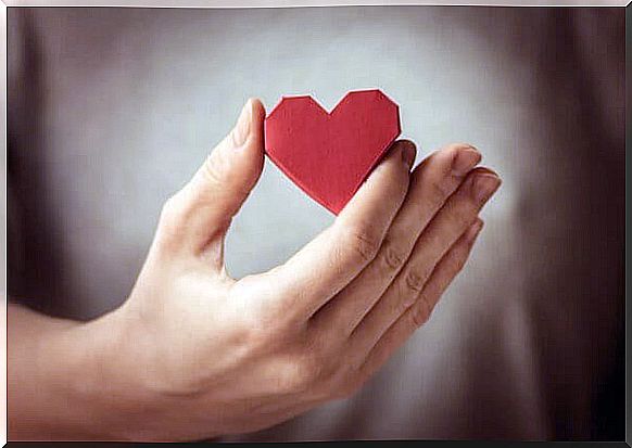 A person holds an origami heart. 