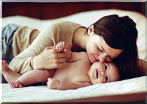 A young mother happily hugs her baby. 