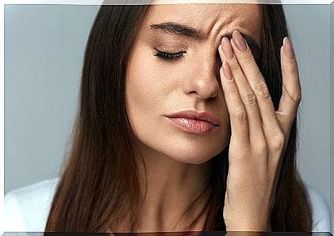 A woman is stressed and holds a hand in front of her face. 