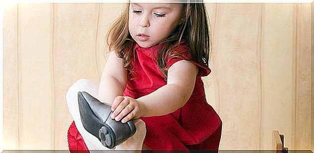 A little girl puts on her right shoe.