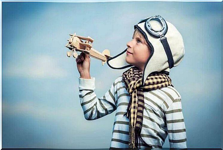 A boy plays with a wooden airplane.