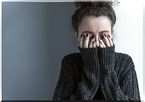 Woman with depression holds hands in front of her face