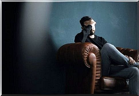 Man is sitting on a couch and leaning his head on his hand