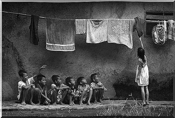 Children sitting under a clothesline