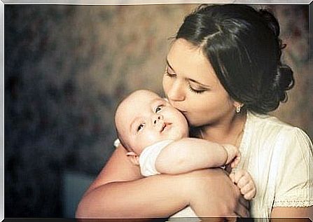 A woman kissing a baby.