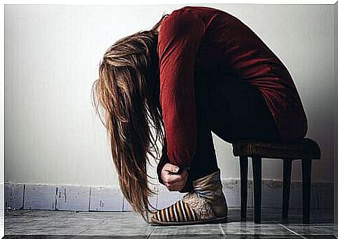 Depressed woman sits huddled in a small chair